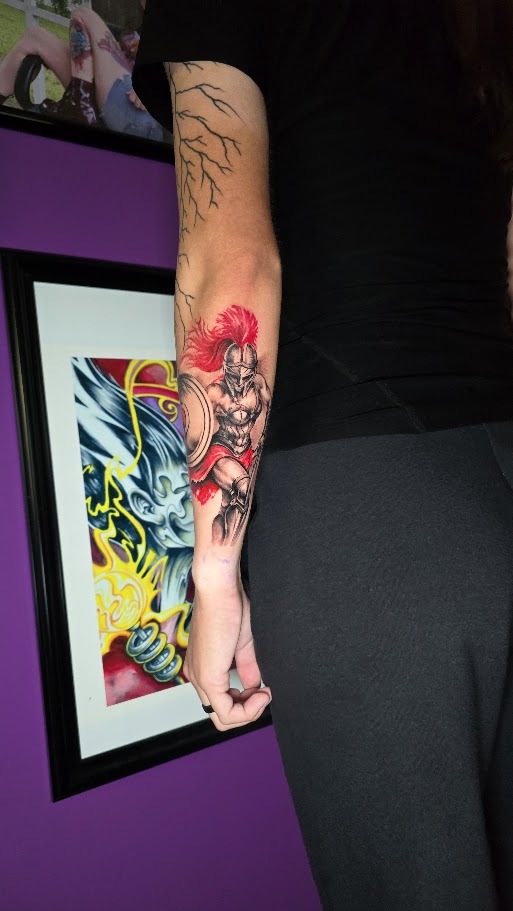 Black and grey Spartan forearm tattoo with red accents by Billy