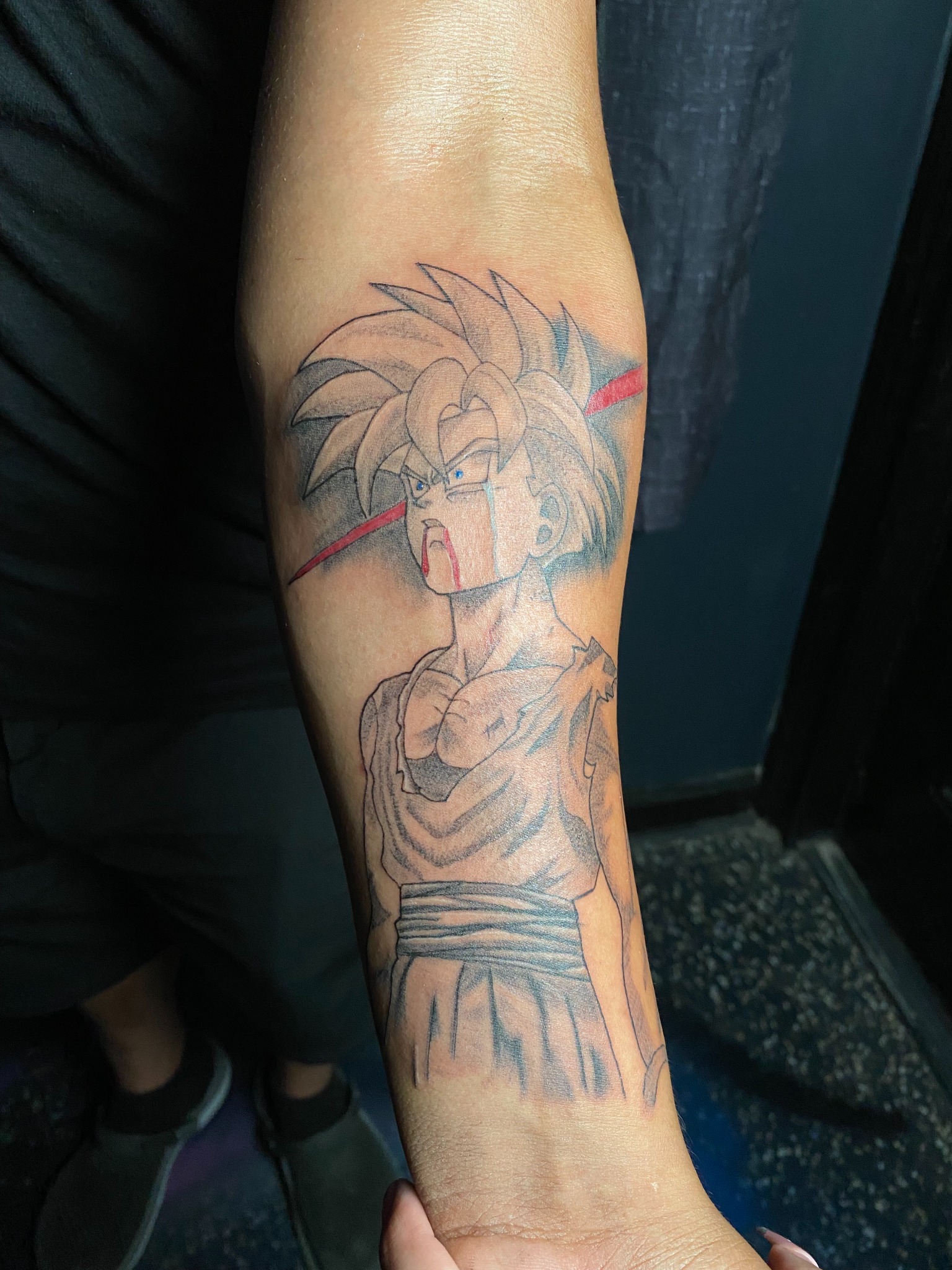 Black and grey Goku forearm tattoo with red accents by Blady